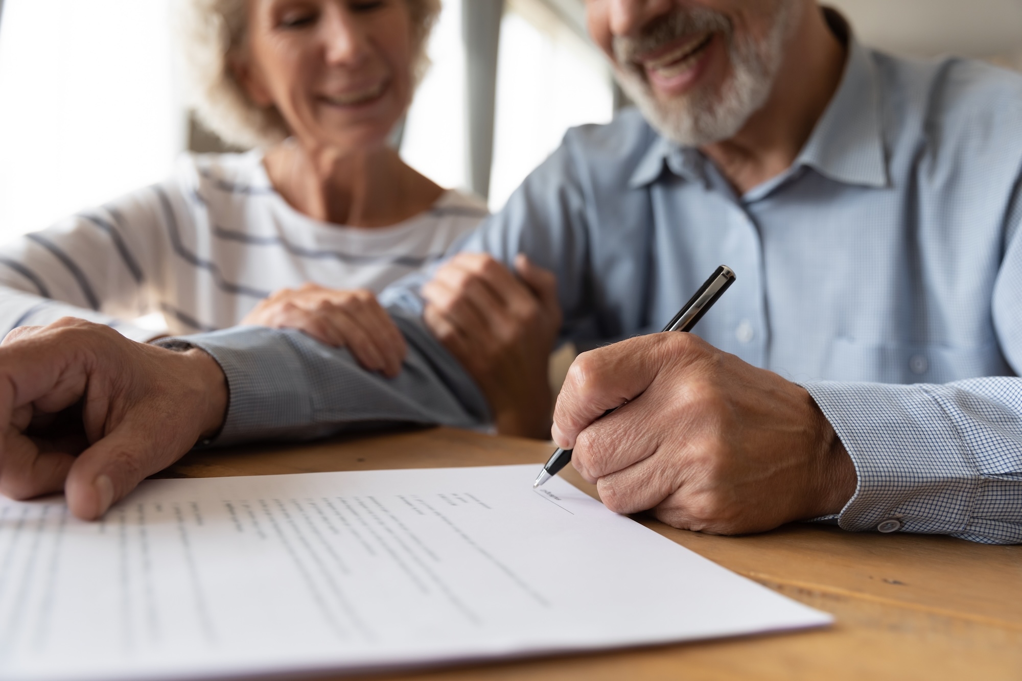 Man signing a will while his wife looks on, illustrating the execution and witnessing requirements under California Probate Code 6110